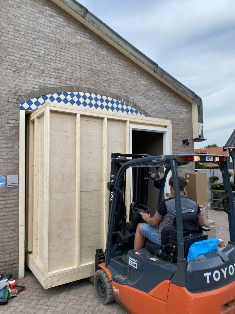Prefab badkamer wordt met een heftruck nauwkeurig op locatie geplaatst